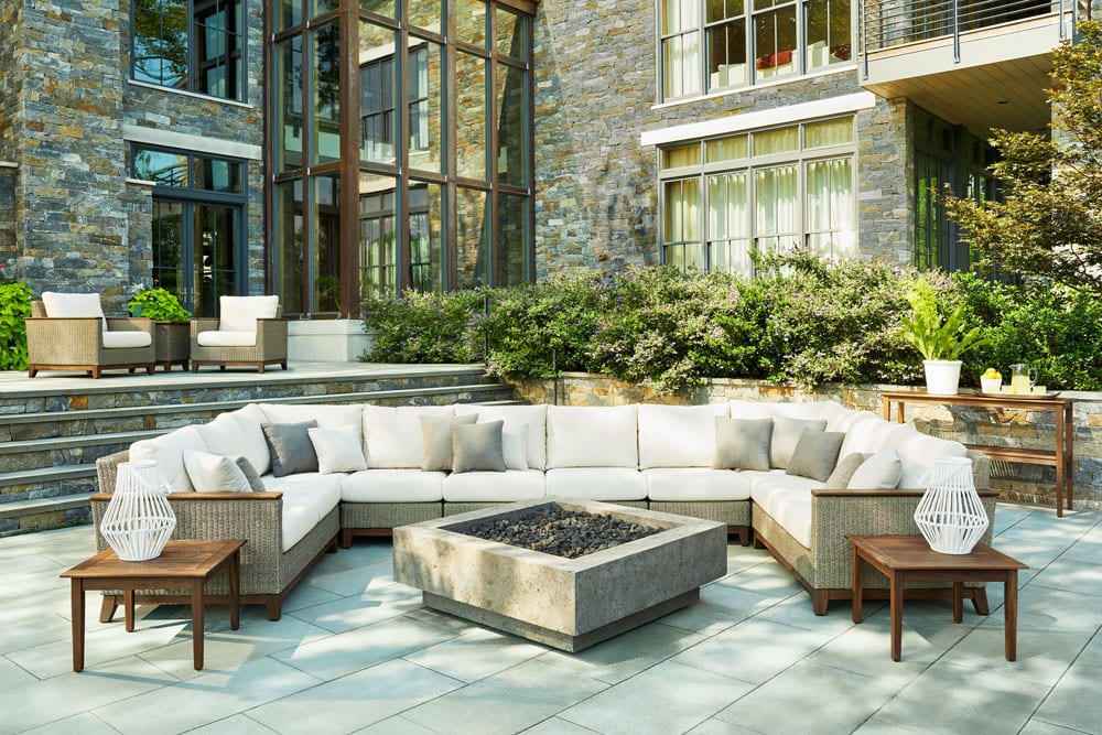 Jensen Coral Sectional patio furniture and fire pit set on the patio behind a brick house