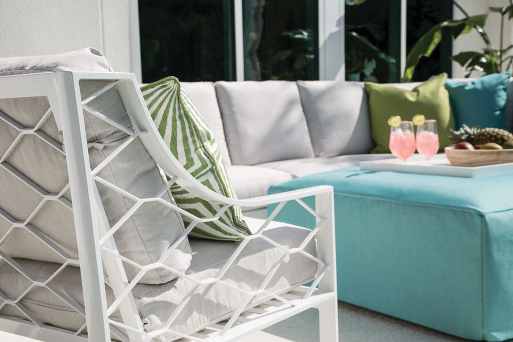 Closeup view of Biscayne Bay couch and armchair outdoor furniture set on the patio behind a luxurious home