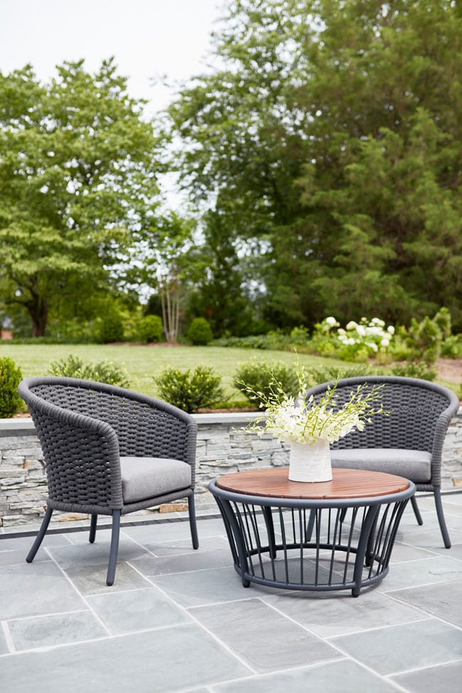 Jensen Leisure outdoor patio furniture on a patio made of stone pavers with a short stone wall behind