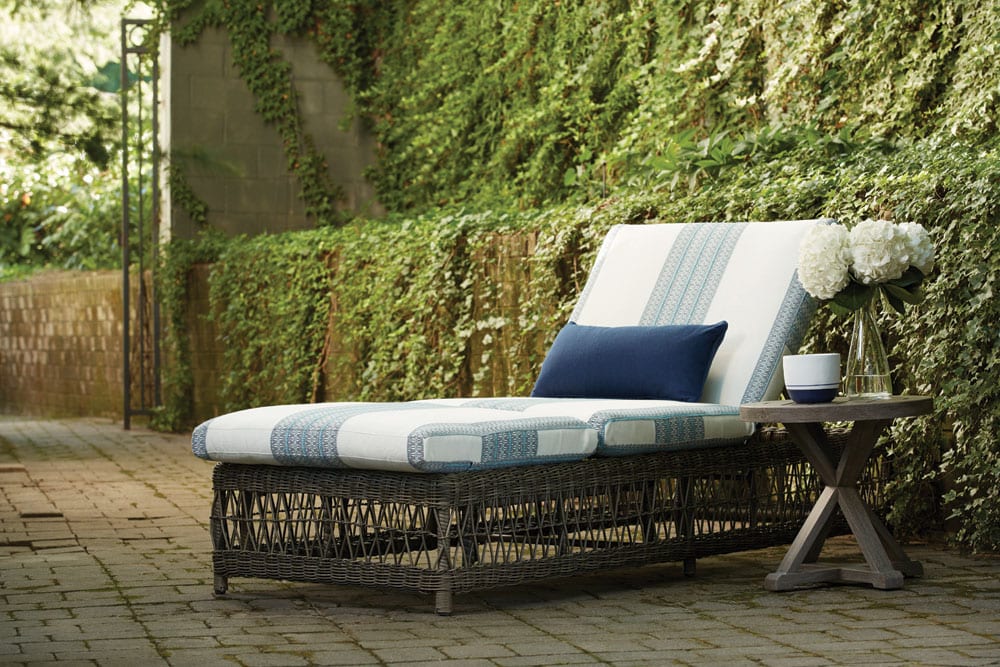 Moraya Bay cushioned chaise outdoor furniture from Lane Venture on stone pavers patio surrounded by a lot of vegetation