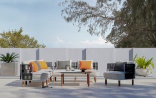 Outdoor patio furniture set with orange and grey pillows on patio in front of wall and potted plants