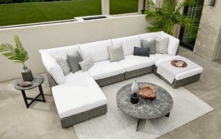 A white wicker outdoor couch set on a rug shows the easy and affordable way to refresh your outdoor space