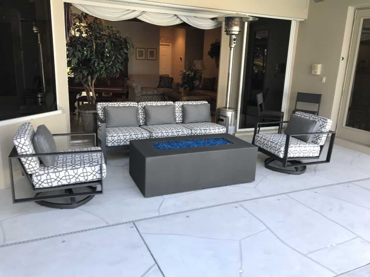 Outdoor couch and lounge chairs surrounding fire pit on patio