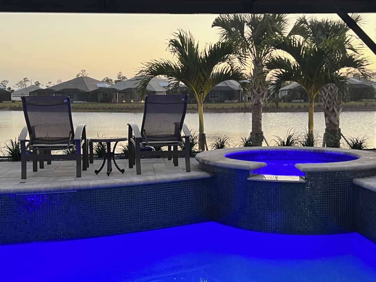 Telescope Casual Furniture lounge chairs with drink table set on patio next to pool